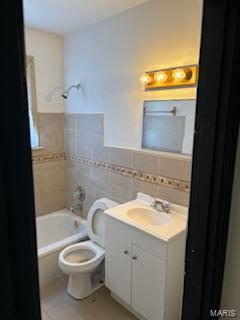 full bathroom with shower / tub combination, vanity, toilet, and tile walls