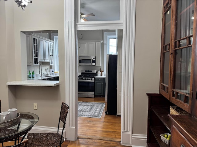 kitchen with stainless steel appliances, ceiling fan, sink, hardwood / wood-style flooring, and white cabinets