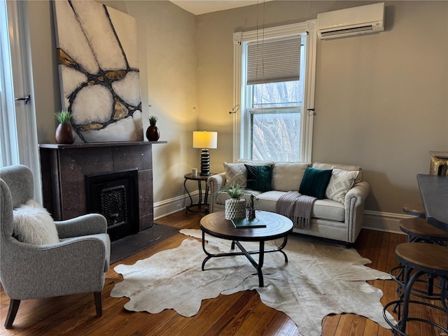 living room with a wall mounted AC, hardwood / wood-style floors, and a tiled fireplace