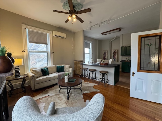 living room featuring ceiling fan, hardwood / wood-style floors, track lighting, and a wall mounted air conditioner