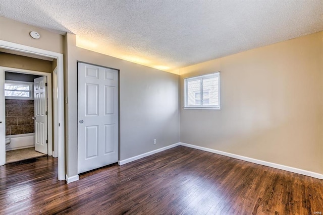 unfurnished bedroom with dark hardwood / wood-style floors and a textured ceiling