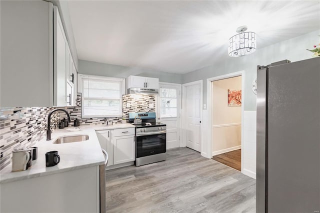 kitchen with white cabinets, appliances with stainless steel finishes, and light hardwood / wood-style flooring