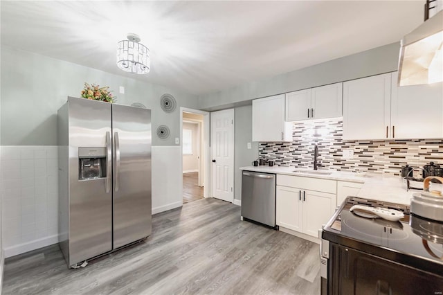 kitchen featuring sink, hanging light fixtures, appliances with stainless steel finishes, white cabinets, and light wood-type flooring