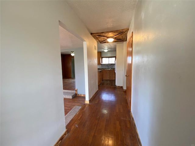 hall featuring a textured ceiling and dark wood-type flooring