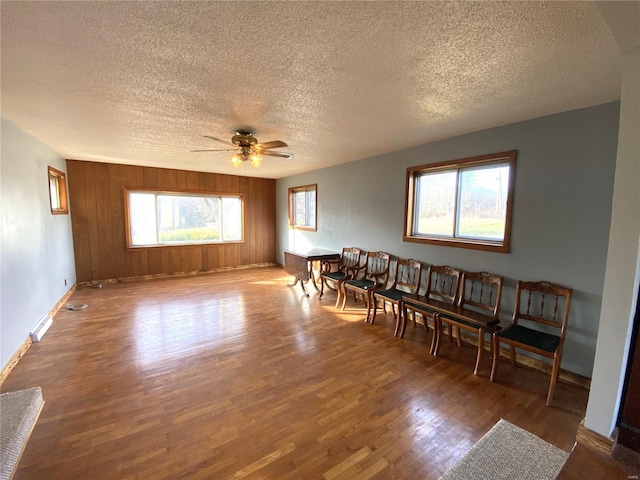 living room featuring dark hardwood / wood-style floors, ceiling fan, a textured ceiling, and wooden walls