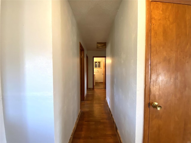 corridor featuring dark hardwood / wood-style flooring and a textured ceiling