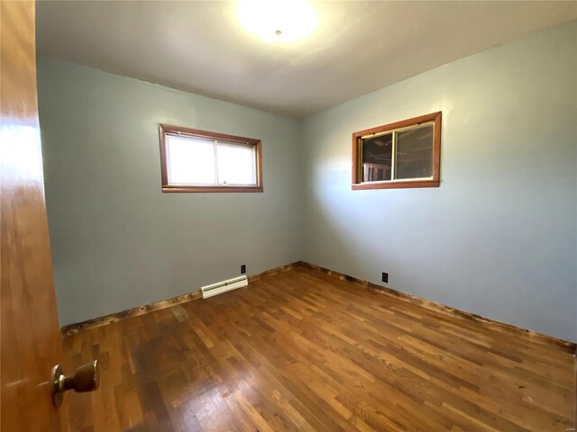 spare room with baseboard heating and dark wood-type flooring