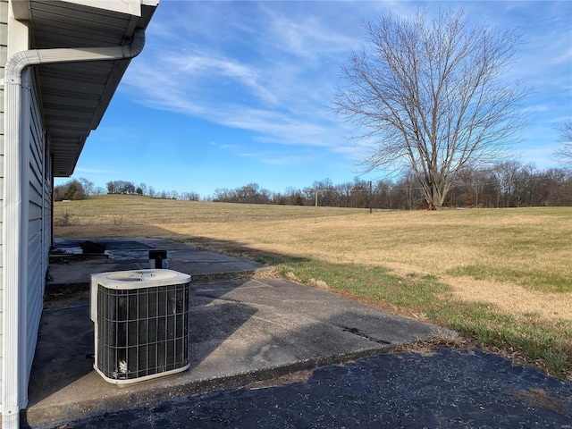 view of yard featuring a rural view and central air condition unit