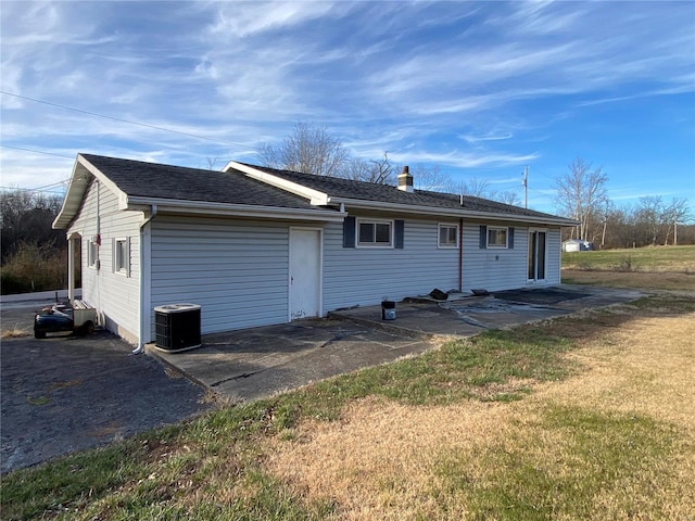 rear view of house featuring a patio, central AC unit, and a lawn