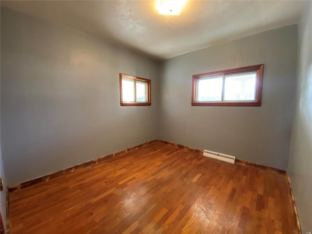 empty room featuring wood-type flooring and a baseboard radiator