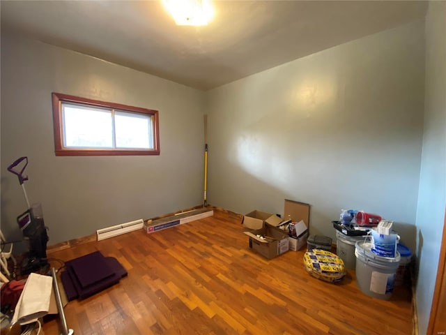 empty room featuring hardwood / wood-style flooring and a baseboard heating unit