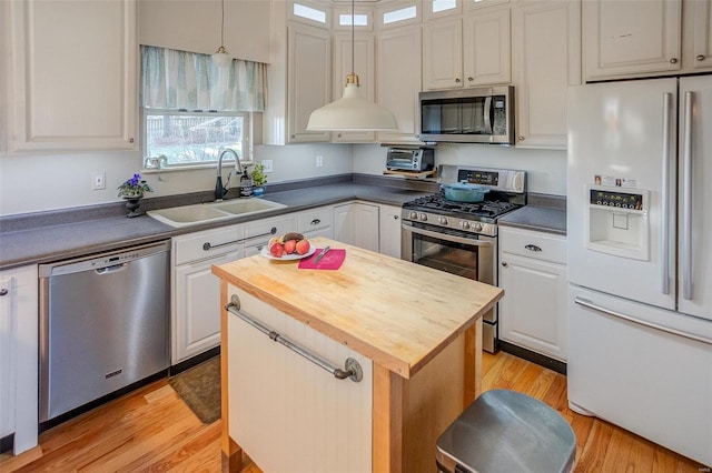 kitchen with a center island, sink, stainless steel appliances, white cabinets, and light wood-type flooring