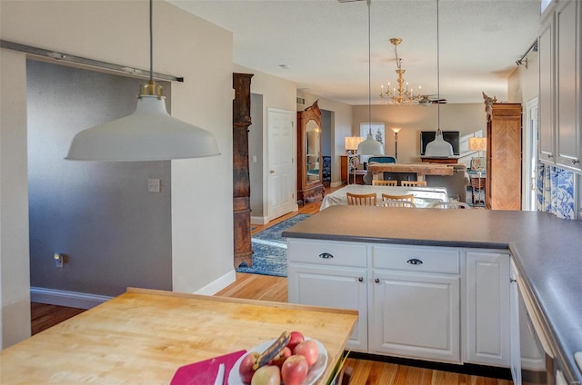 kitchen with hardwood / wood-style floors, an inviting chandelier, white cabinetry, and hanging light fixtures