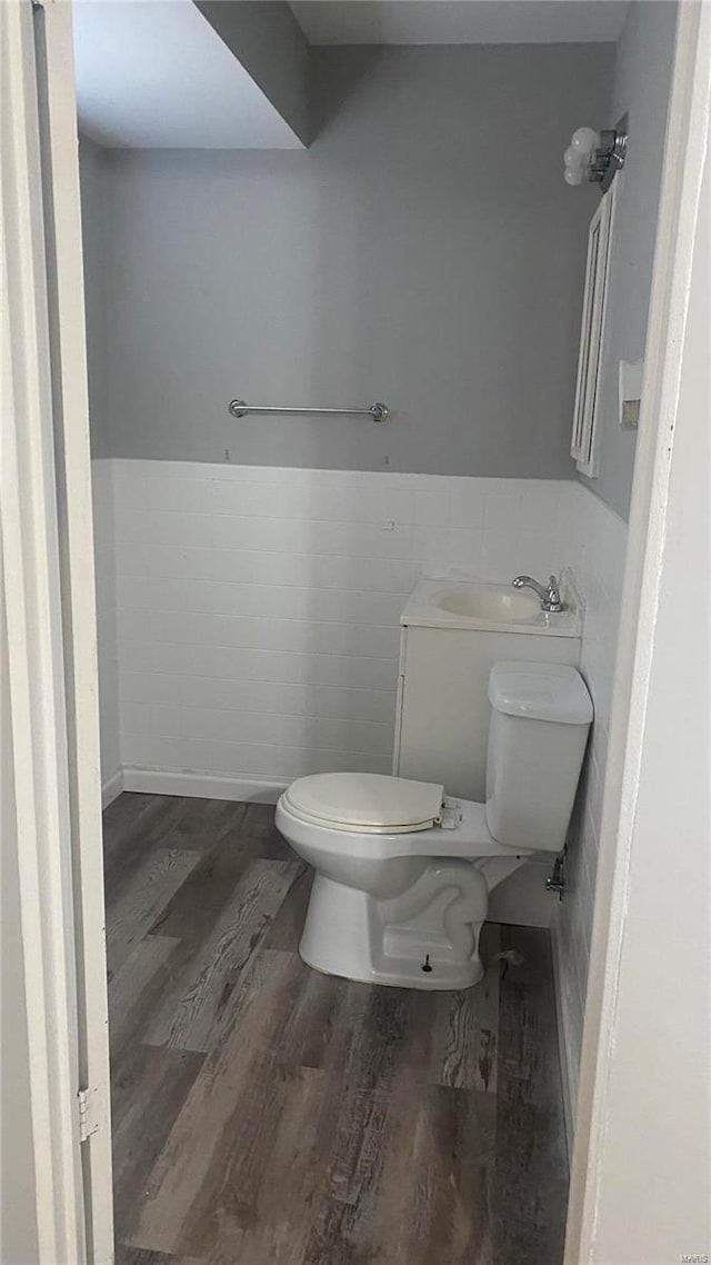 bathroom featuring sink, toilet, wood-type flooring, and tile walls