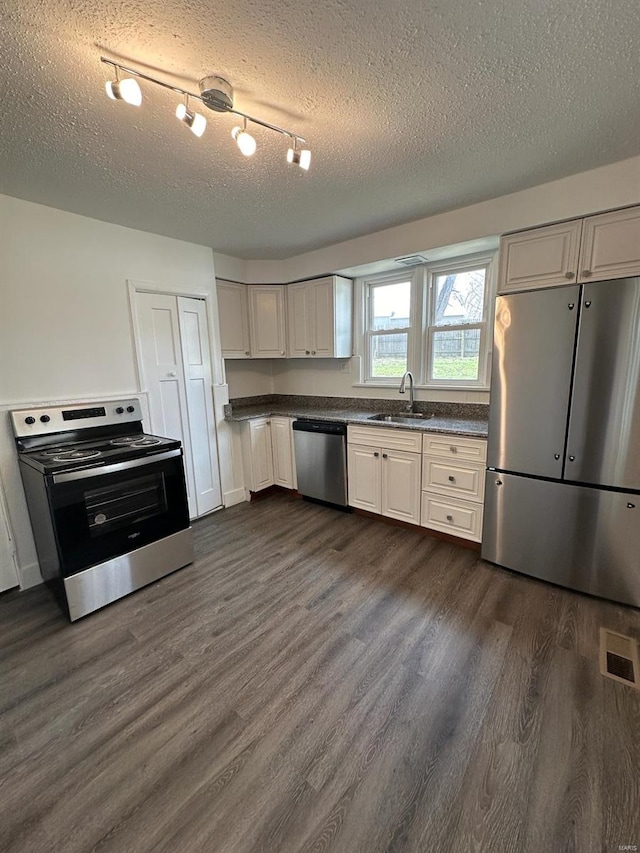 kitchen featuring white cabinetry, sink, stainless steel appliances, dark hardwood / wood-style floors, and a textured ceiling