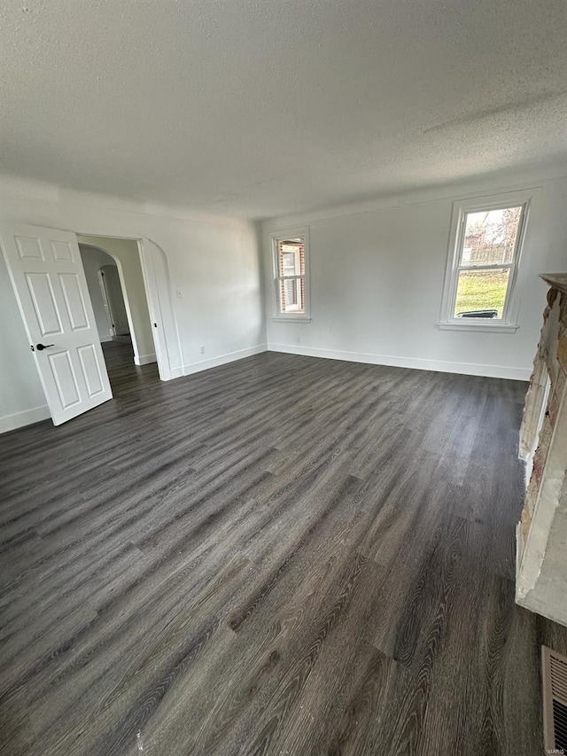 unfurnished living room featuring a fireplace, dark wood-type flooring, and a textured ceiling