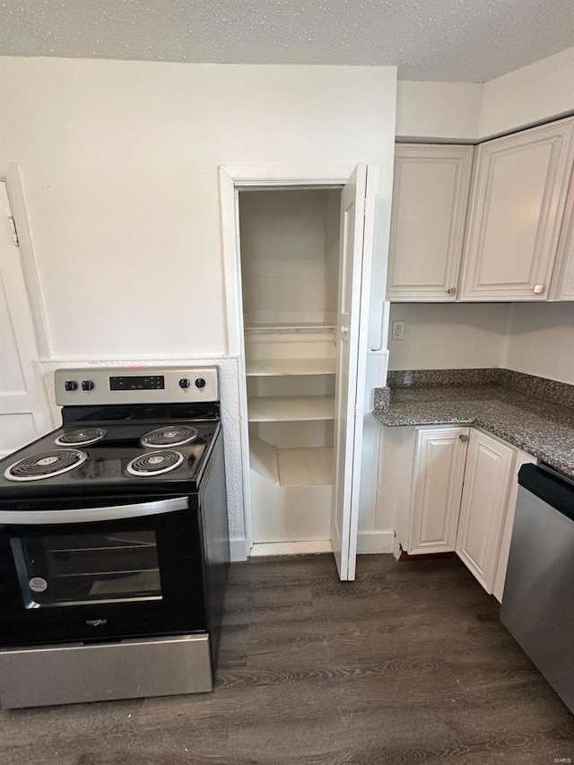 kitchen with dark hardwood / wood-style flooring, white cabinets, stainless steel appliances, and a textured ceiling