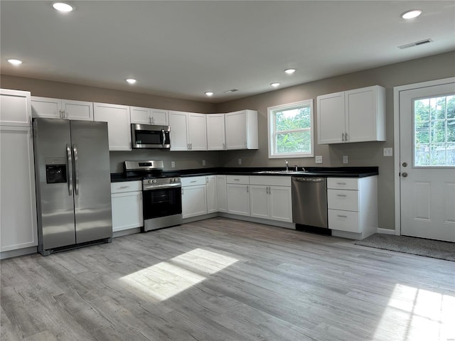 kitchen featuring sink, white cabinets, light wood-type flooring, and appliances with stainless steel finishes