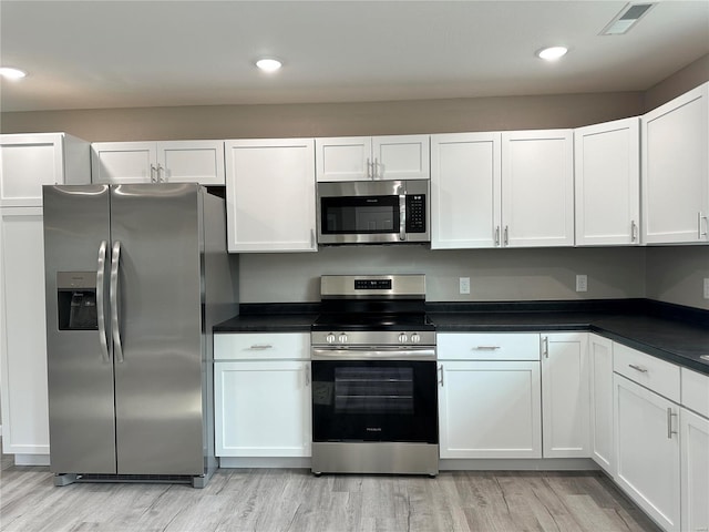 kitchen with white cabinets, light hardwood / wood-style floors, and stainless steel appliances