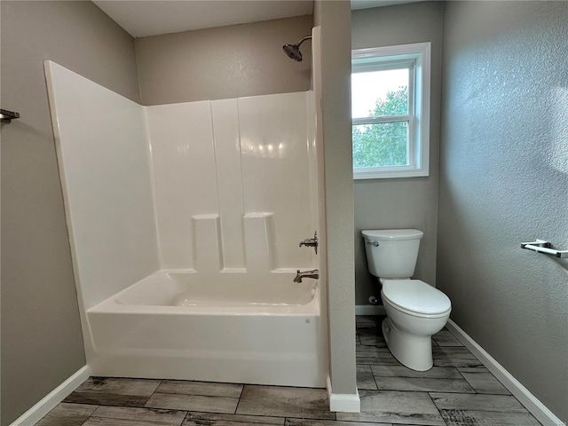 bathroom with hardwood / wood-style floors, shower / bathtub combination, and toilet