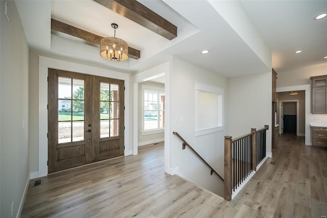 foyer entrance featuring french doors, a chandelier, and light hardwood / wood-style floors