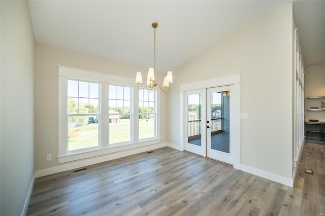 unfurnished dining area featuring lofted ceiling, light hardwood / wood-style flooring, french doors, and a notable chandelier