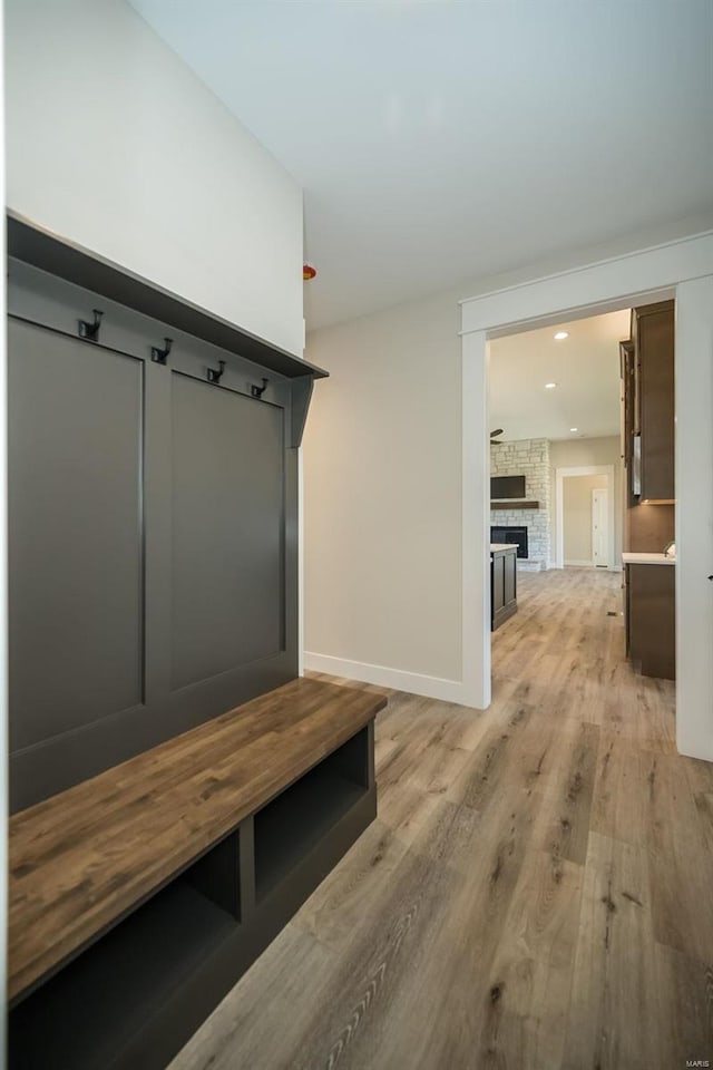 mudroom featuring a stone fireplace and light hardwood / wood-style flooring