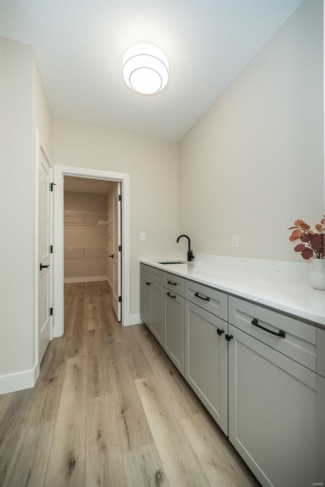 kitchen with gray cabinetry, sink, and light hardwood / wood-style floors