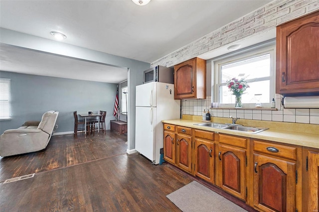 kitchen with dark hardwood / wood-style floors, white fridge, decorative backsplash, and sink