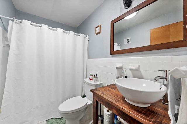 bathroom with a shower with shower curtain, toilet, sink, and tile walls