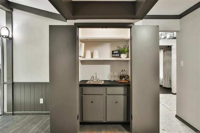 bar with gray cabinetry, light hardwood / wood-style floors, ornamental molding, and sink