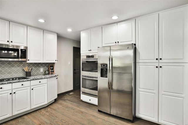 kitchen with decorative backsplash, dark hardwood / wood-style flooring, stainless steel appliances, and white cabinetry