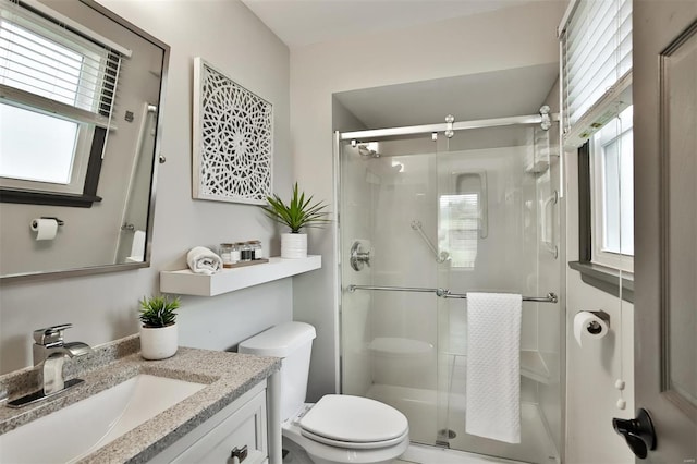 bathroom with an enclosed shower, vanity, a healthy amount of sunlight, and toilet