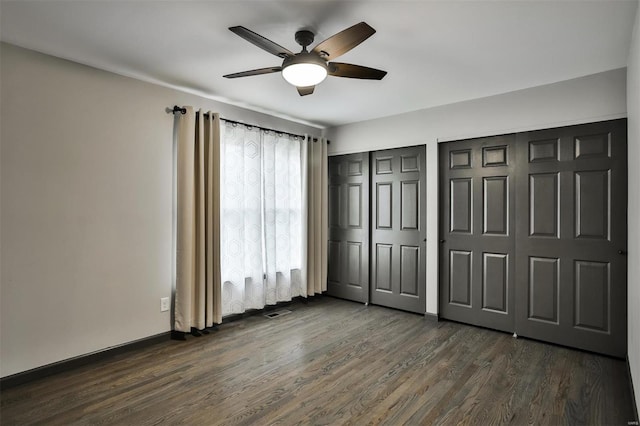 unfurnished bedroom featuring two closets, ceiling fan, and dark hardwood / wood-style floors