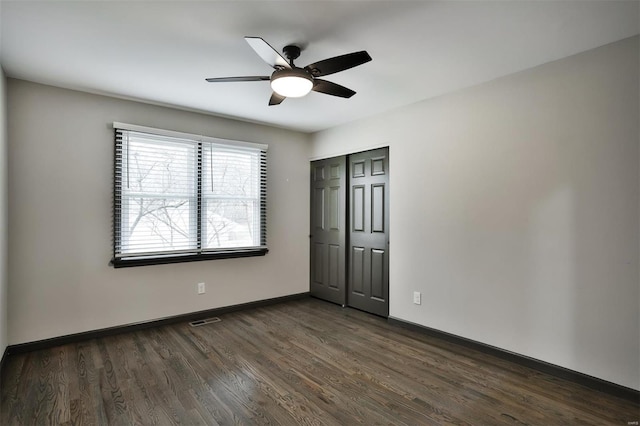 unfurnished bedroom with ceiling fan, dark wood-type flooring, and a closet