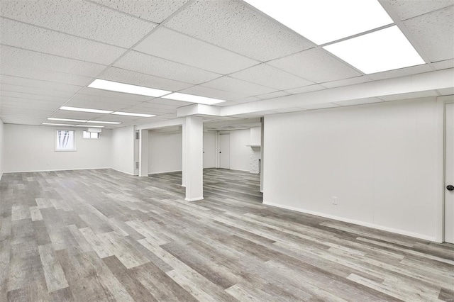 basement featuring a paneled ceiling and wood-type flooring