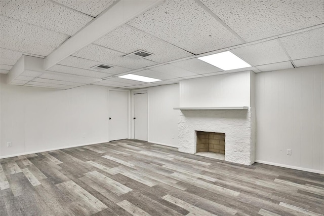 basement featuring a drop ceiling, wood-type flooring, and a fireplace