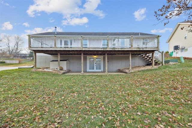 rear view of property featuring french doors, a deck, and a lawn