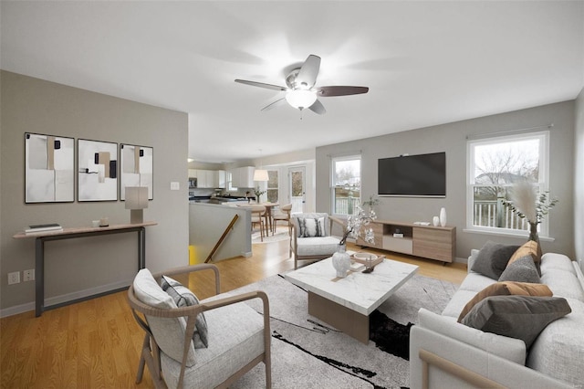 living room featuring plenty of natural light, ceiling fan, and light wood-type flooring