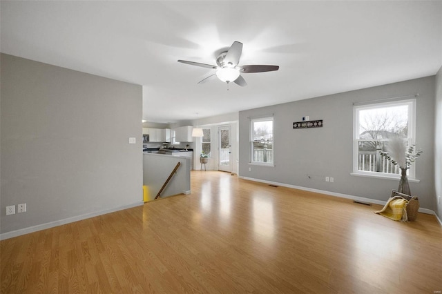 unfurnished living room featuring ceiling fan, light wood-type flooring, and a wealth of natural light