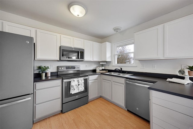 kitchen featuring appliances with stainless steel finishes, light hardwood / wood-style floors, white cabinetry, and sink