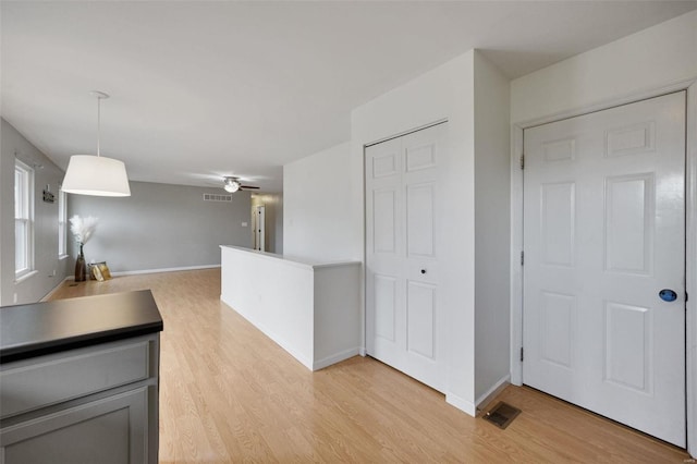 kitchen featuring ceiling fan, light hardwood / wood-style floors, and hanging light fixtures