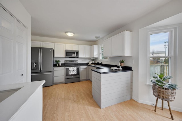 kitchen with white cabinets, sink, stainless steel appliances, and light hardwood / wood-style flooring