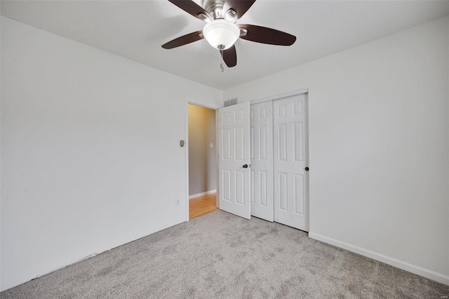 unfurnished bedroom with ceiling fan, a closet, and light carpet