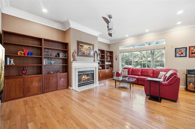 living room featuring ceiling fan, ornamental molding, and light wood-type flooring