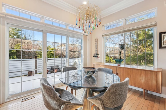 dining room featuring a notable chandelier, crown molding, and light hardwood / wood-style flooring