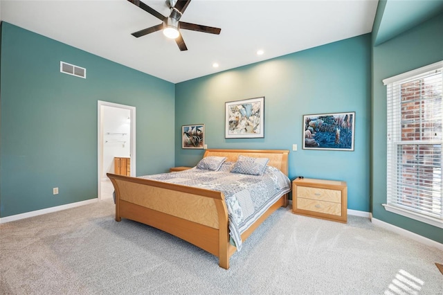 bedroom featuring ensuite bathroom, light colored carpet, and ceiling fan