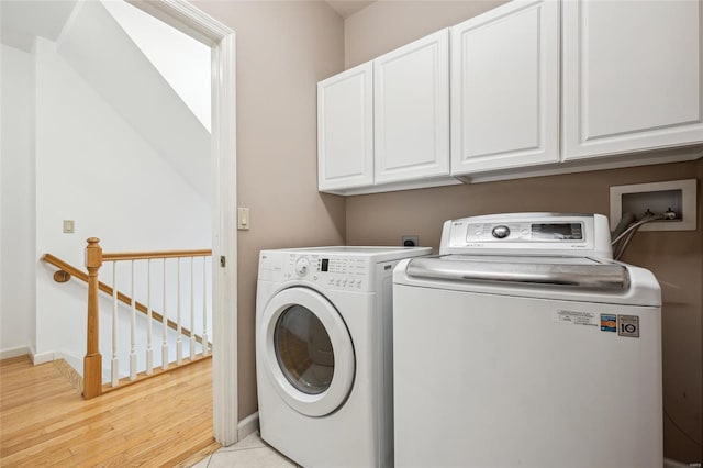 laundry room featuring washing machine and dryer, cabinets, and light tile patterned flooring