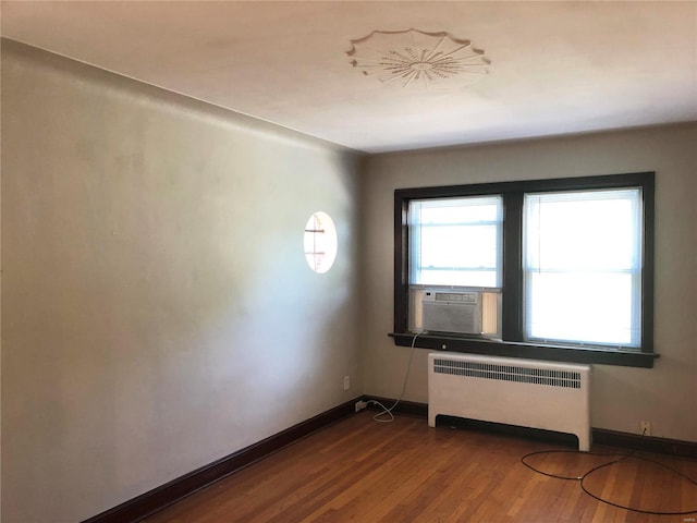 unfurnished room featuring radiator, hardwood / wood-style floors, and cooling unit