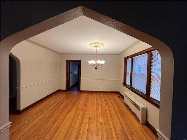 unfurnished room with an inviting chandelier, light hardwood / wood-style flooring, and a baseboard radiator